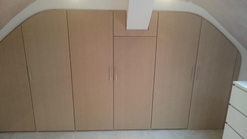 Bespoke fitted wardrobes built into the sloping ceiling of a loft room, primed ready for painting