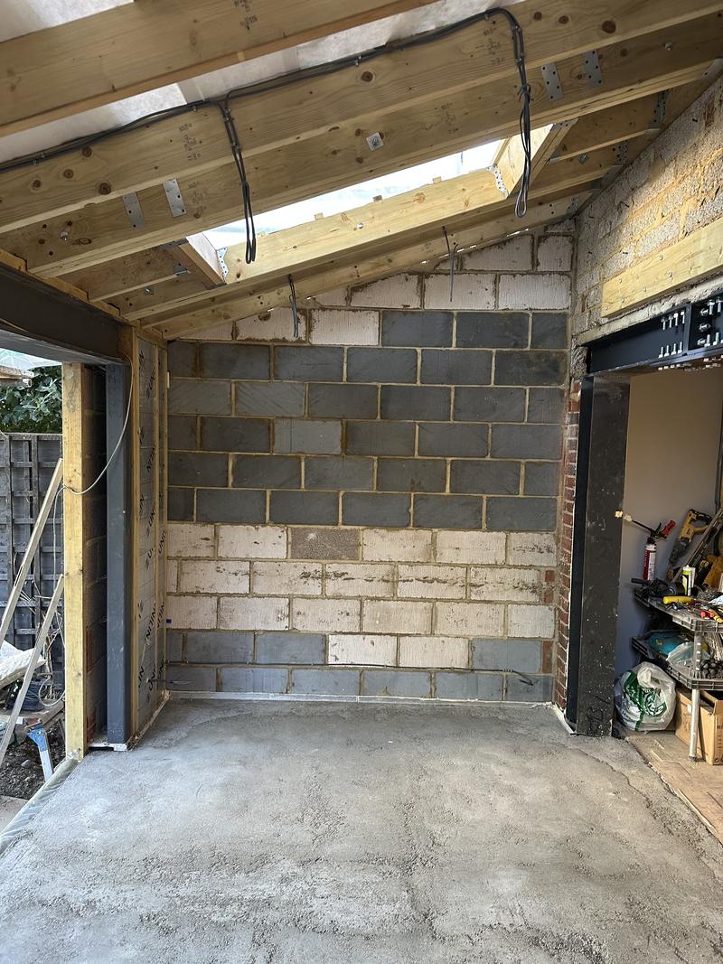Blockwork shell of a single-storey extension with the roof structure open and a rooflight above
