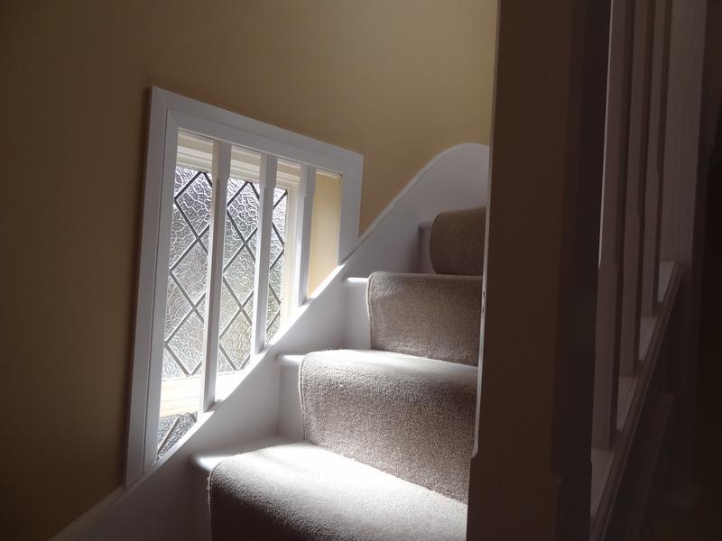 Carpeted staircase turning past a leaded window on the way up to the loft