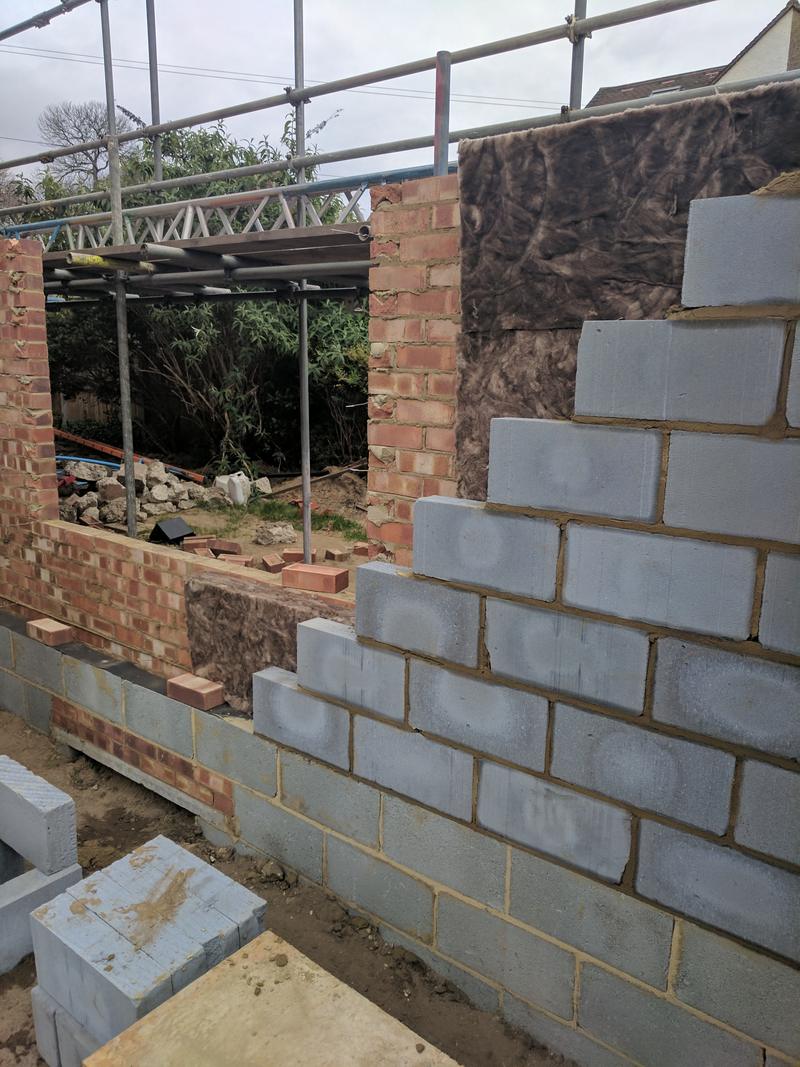 Cavity walls being built for a rear extension, with insulation and a formed opening