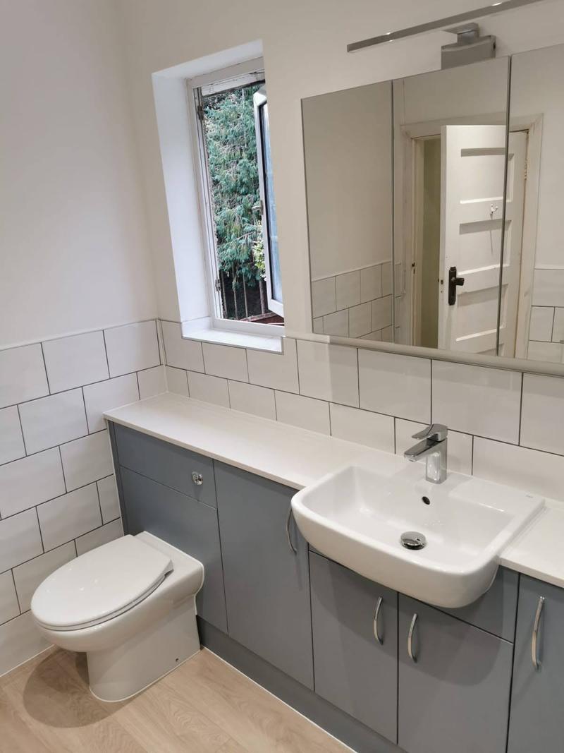Compact shower room with a grey vanity unit, metro tiling and a large mirror