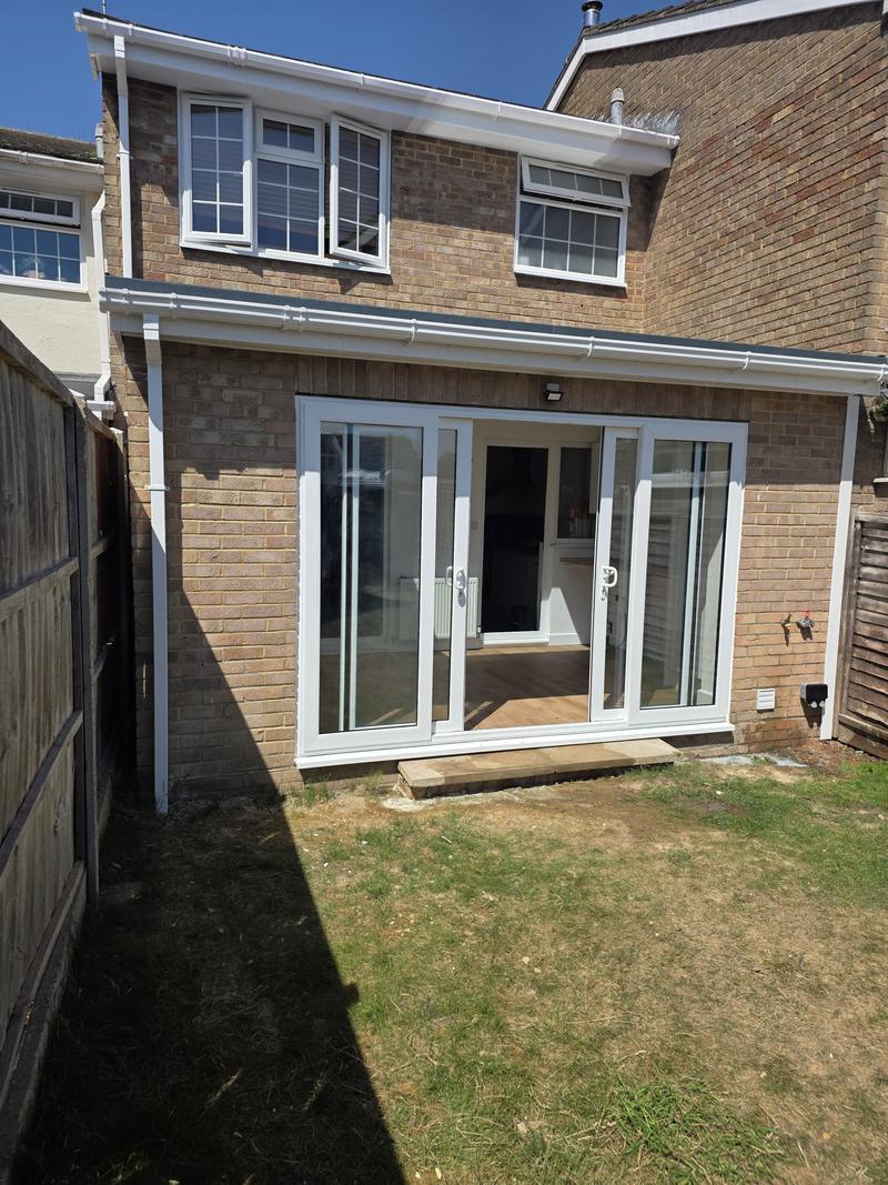Completed single-storey rear extension in brick with a full-width set of white sliding doors opening onto the garden