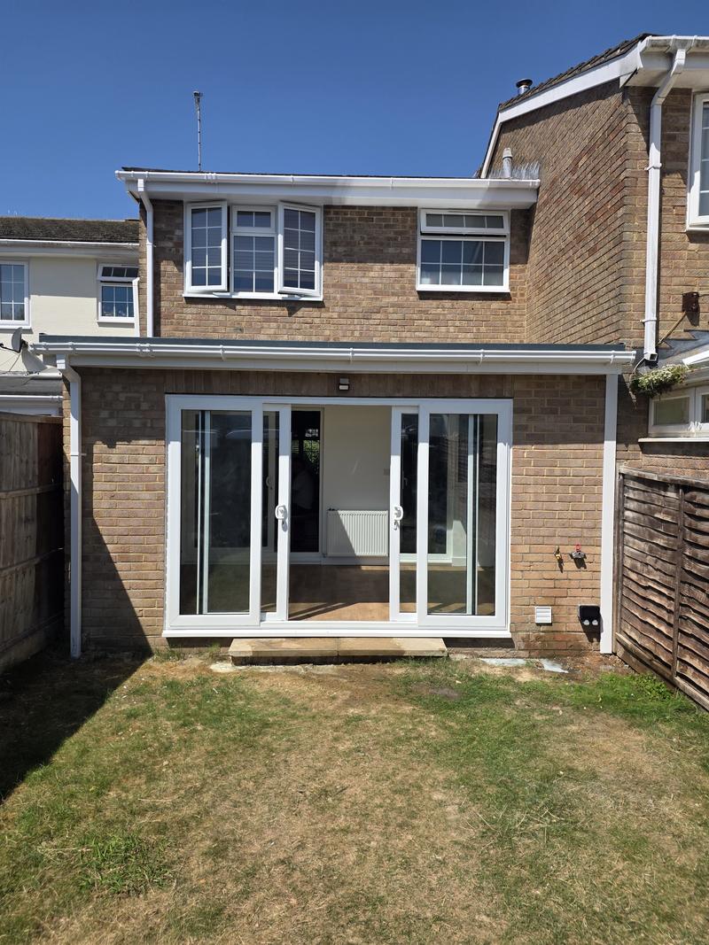 Completed single-storey rear extension in matched buff brickwork with white fascia and wide sliding doors