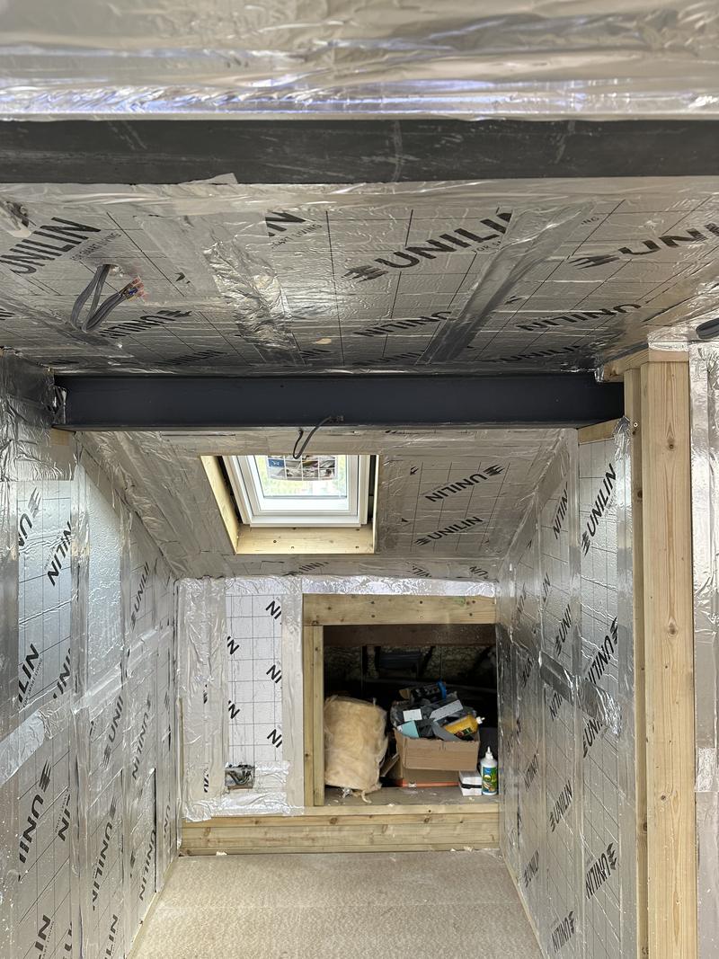 Dormer under construction, lined with foil-faced insulation, a rooflight fitted and the stair opening cut through the floor