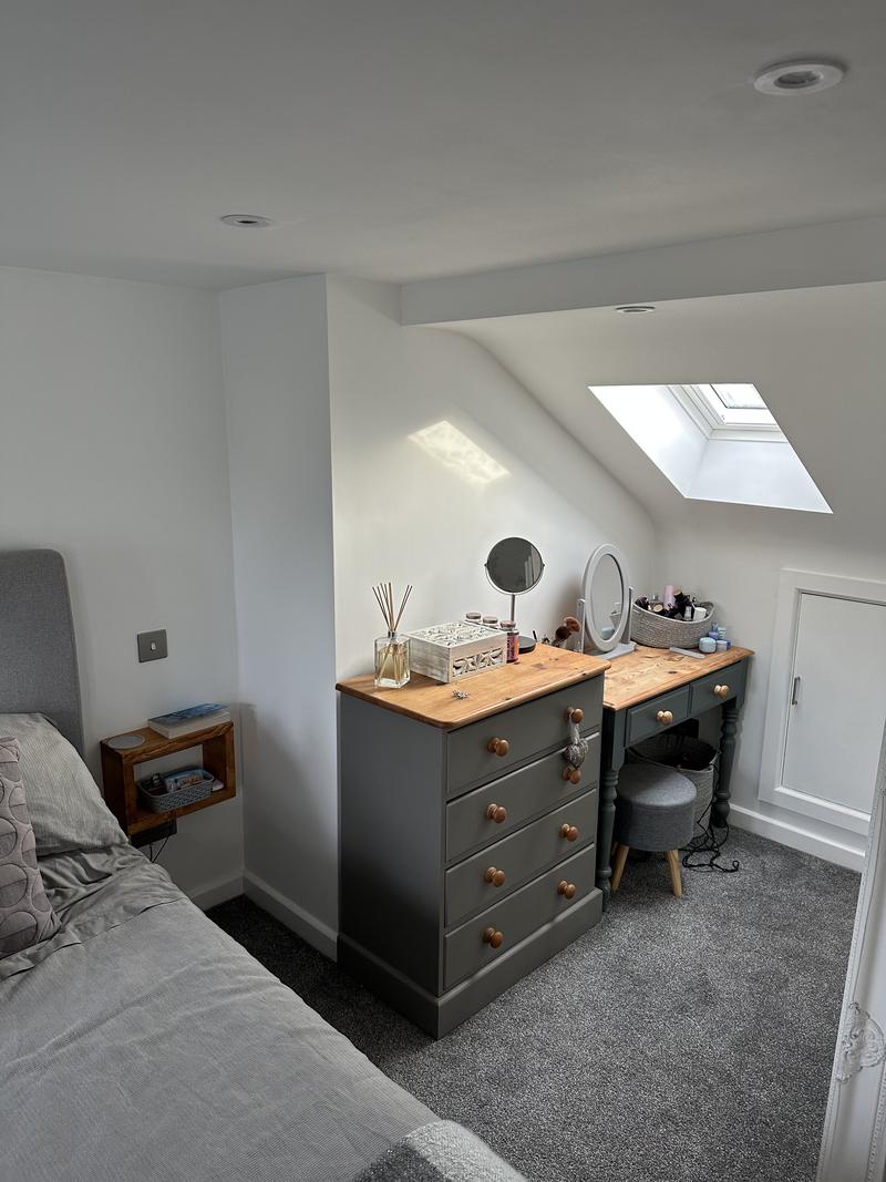 Finished loft bedroom with a dressing table under a rooflight and storage built into the eaves