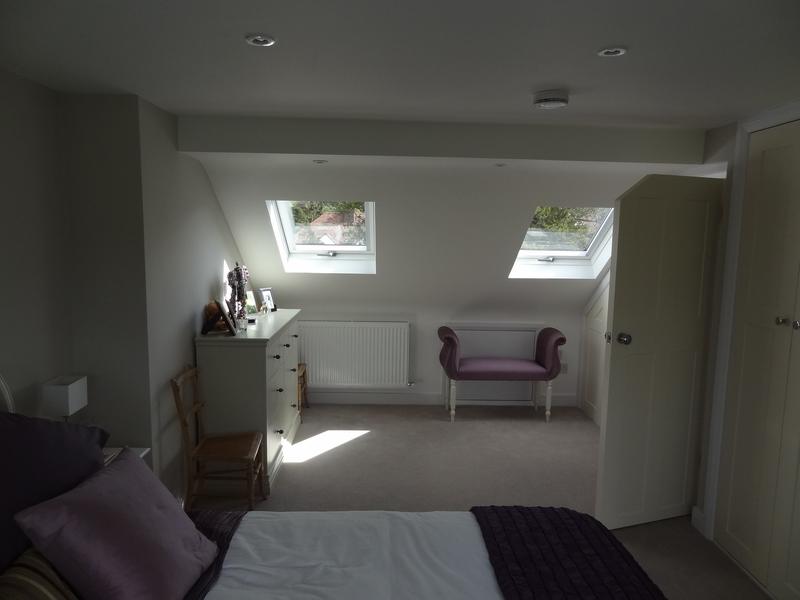 Finished loft bedroom with two rooflights, a chest of drawers, a radiator under the eaves and painted doors either side