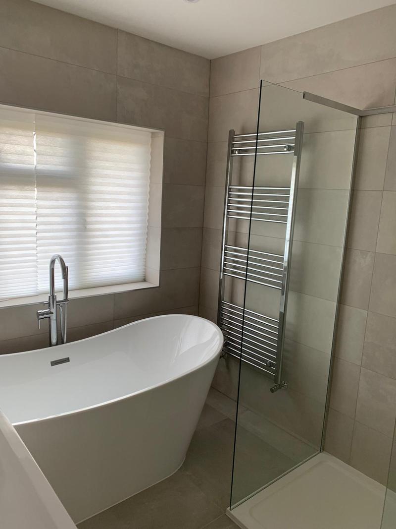 Freestanding slipper bath beside a walk-in shower in a grey tiled family bathroom
