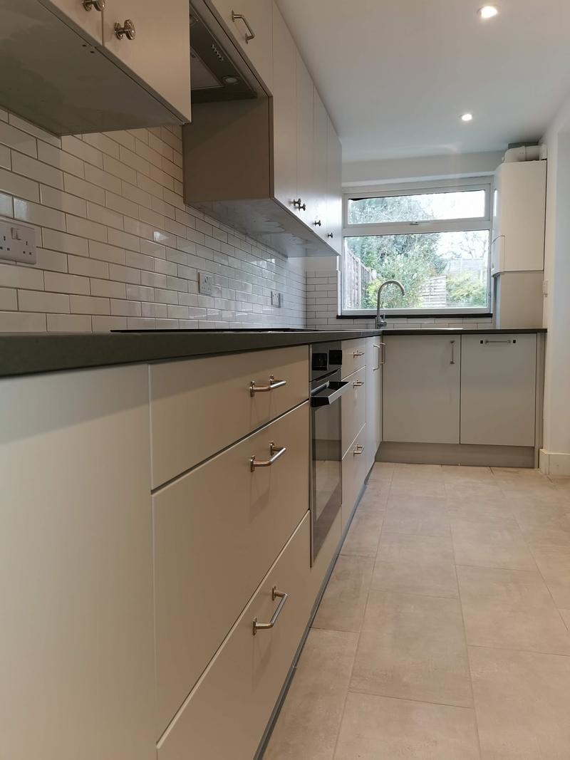 Handleless cream kitchen with a dark worktop and metro tile splashback