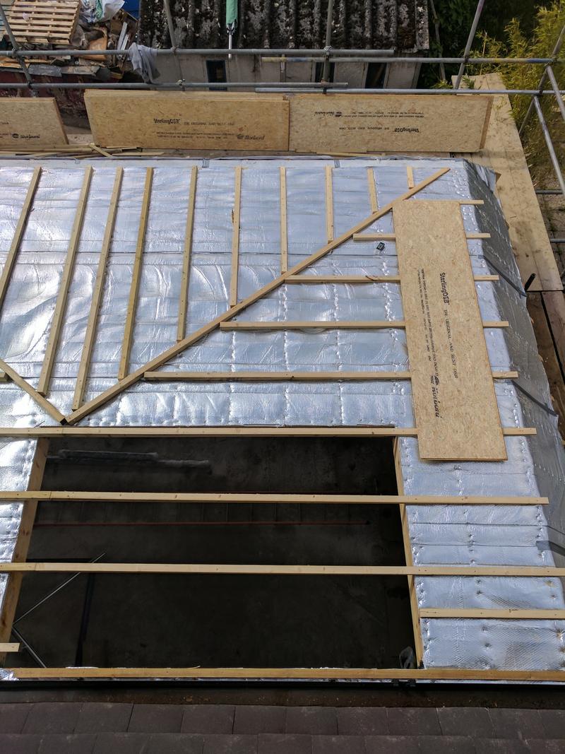 Insulated warm flat roof under construction with two rectangular rooflight openings formed