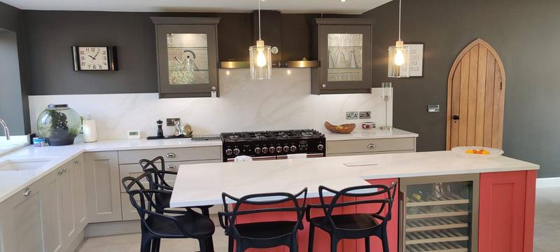Kitchen island with a coral painted end panel, integrated wine cooler and an arched oak door beyond