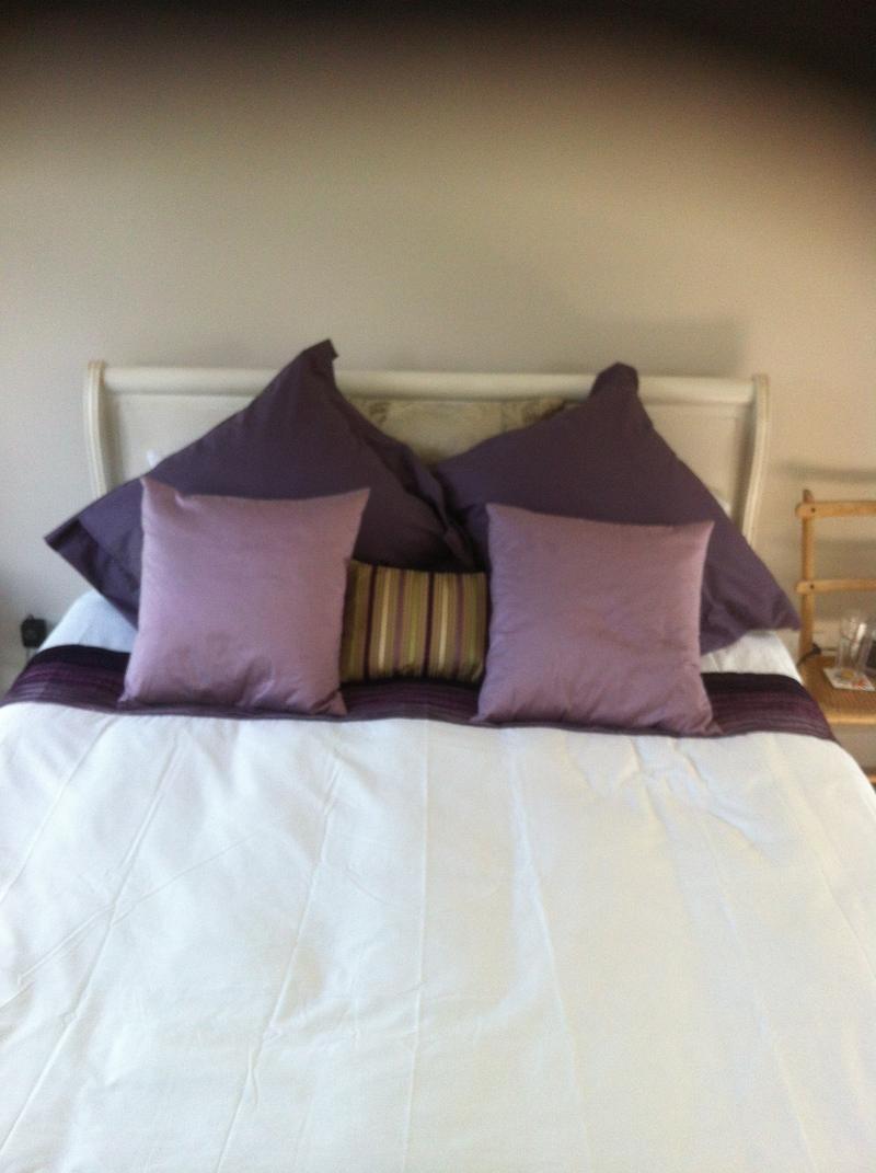 Made bed with cushions against a headboard in the finished loft bedroom