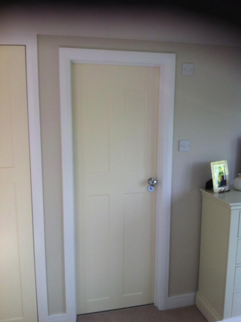 Painted panelled door in a loft bedroom with a chest of drawers beside it