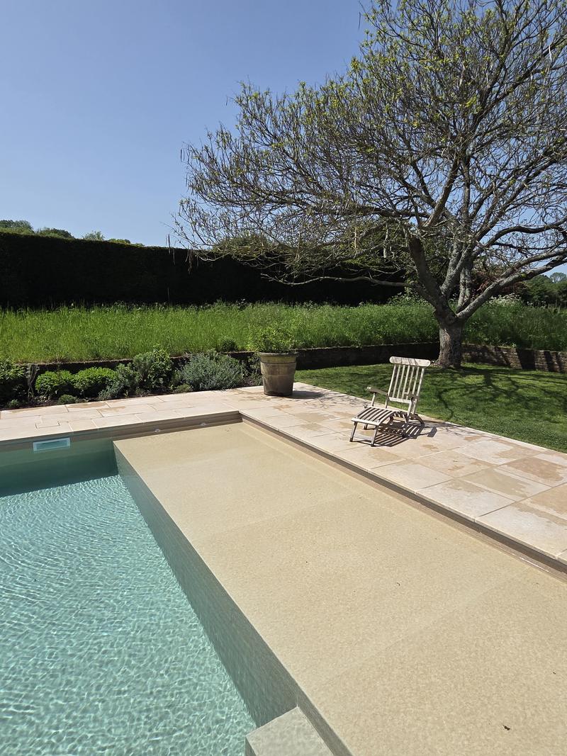 Pool and sandstone terrace looking back towards the garden and the mature trees