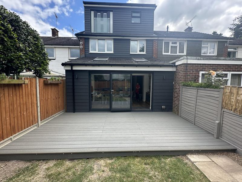 Rear of a house with a dark-clad dormer loft conversion above a single-storey extension with grey bifold doors onto decking