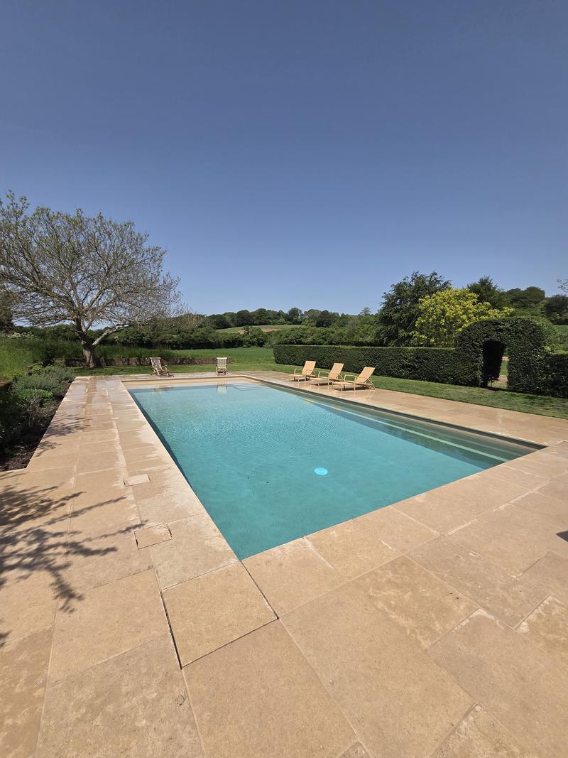 Rectangular pool with a wide sandstone surround and open fields behind