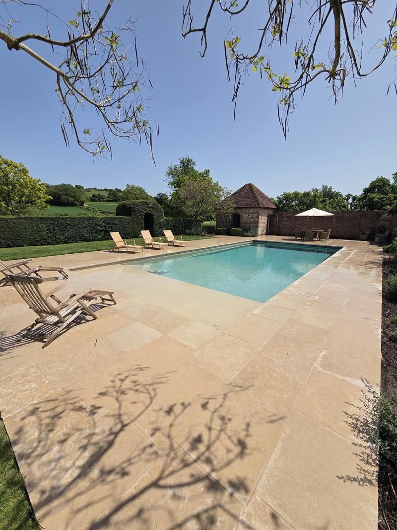 Sandstone terrace running the full length of the pool with the pool house at the end
