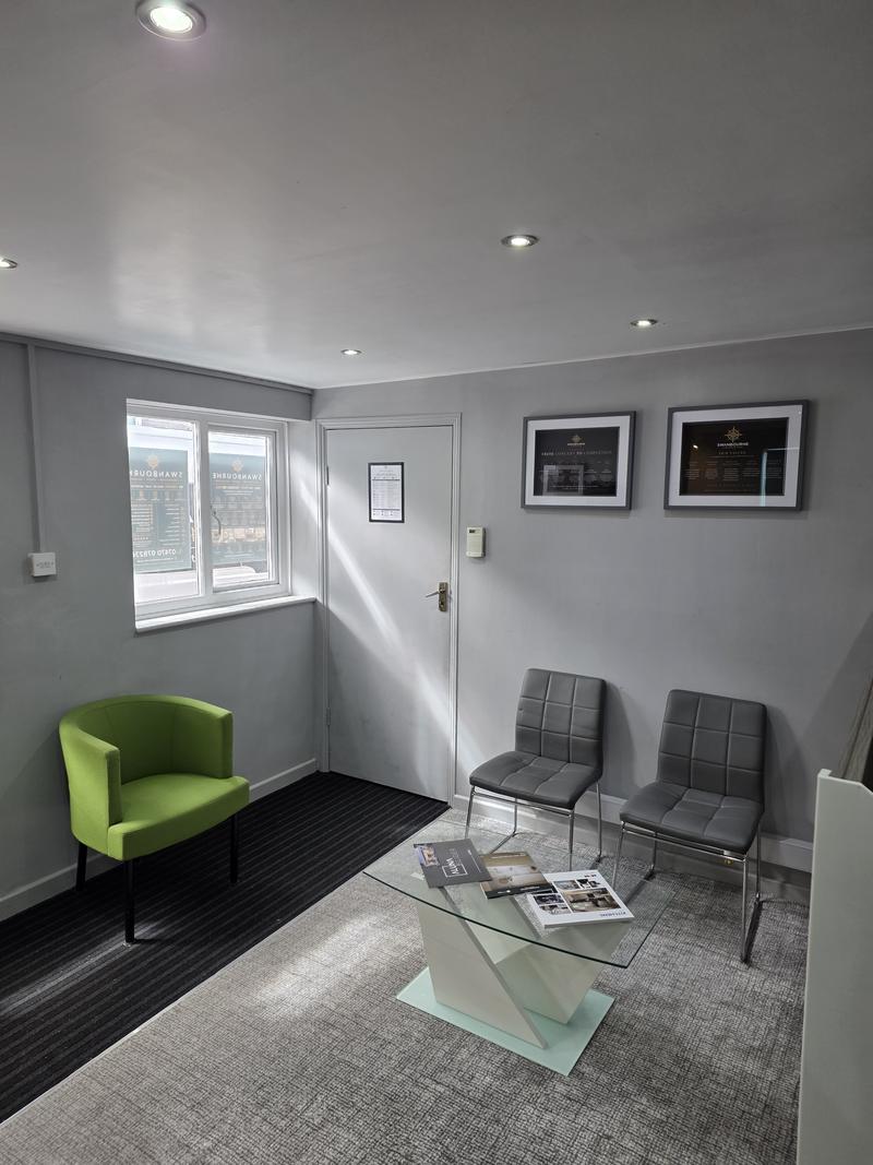 Seating area inside the showroom with framed panels and brochures on a glass table