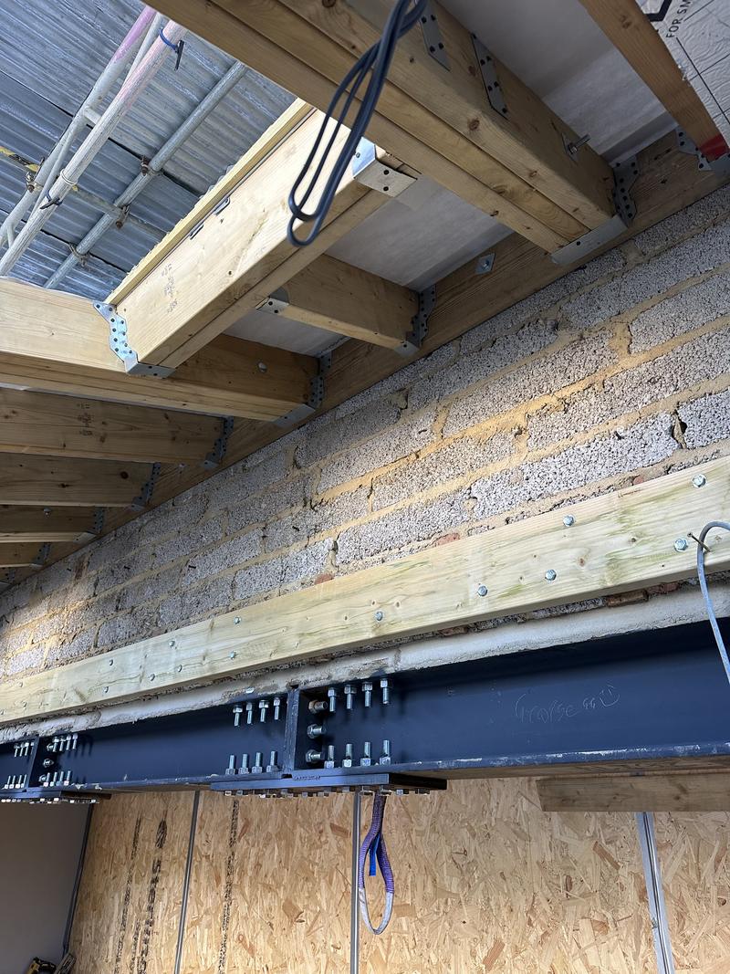 Steel beam with new timber joists sitting in galvanised hangers, insulation boards fixed between the rafters above