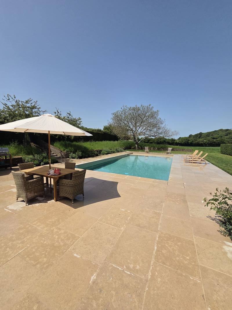 Terrace furniture and a parasol on the sandstone beside the pool