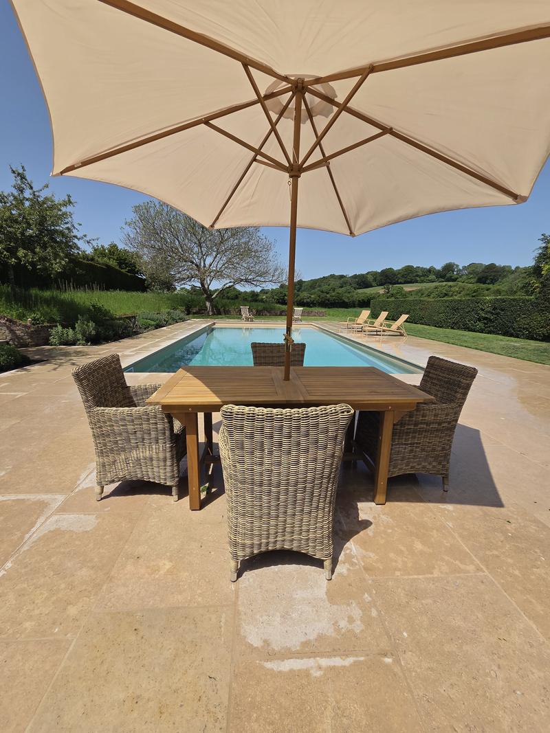 Timber table and wicker chairs under a parasol on the sandstone terrace