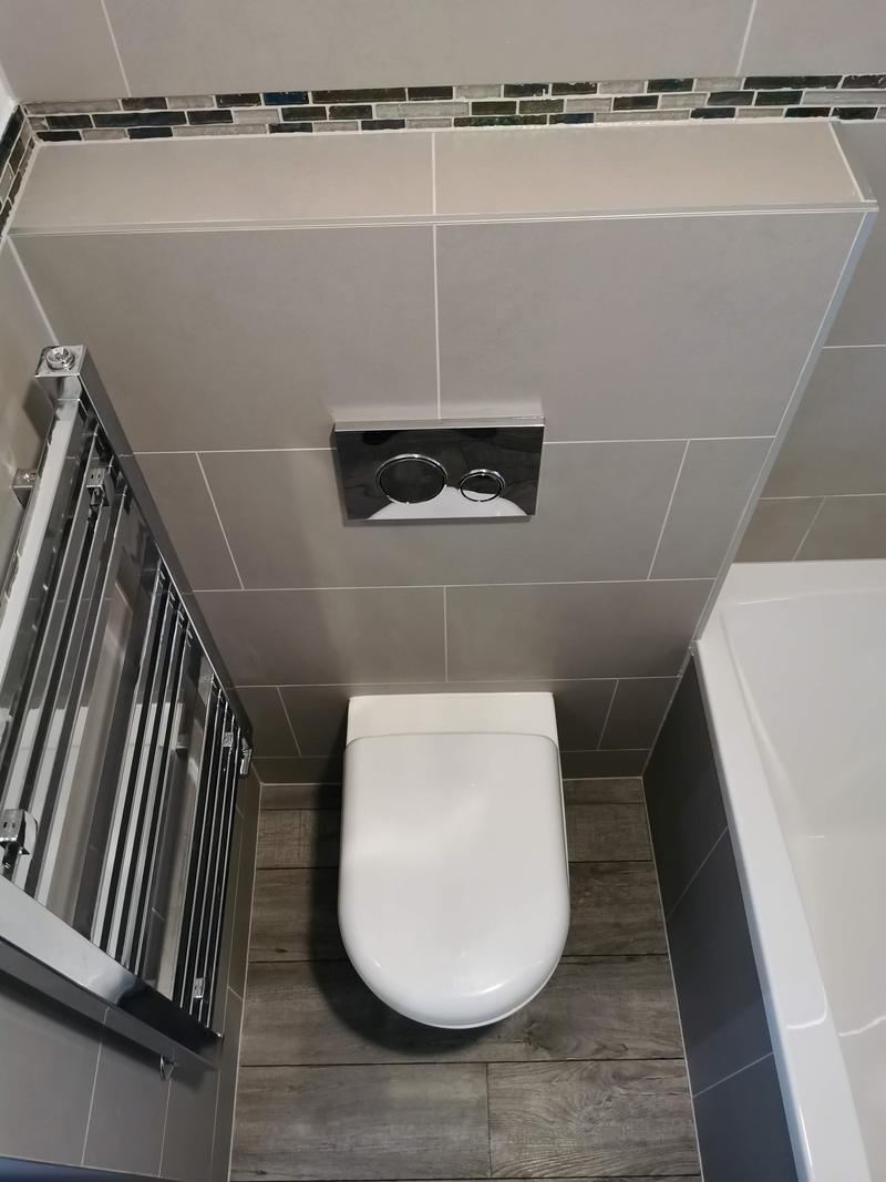 Wall-hung WC and chrome ladder radiator in a grey tiled bathroom